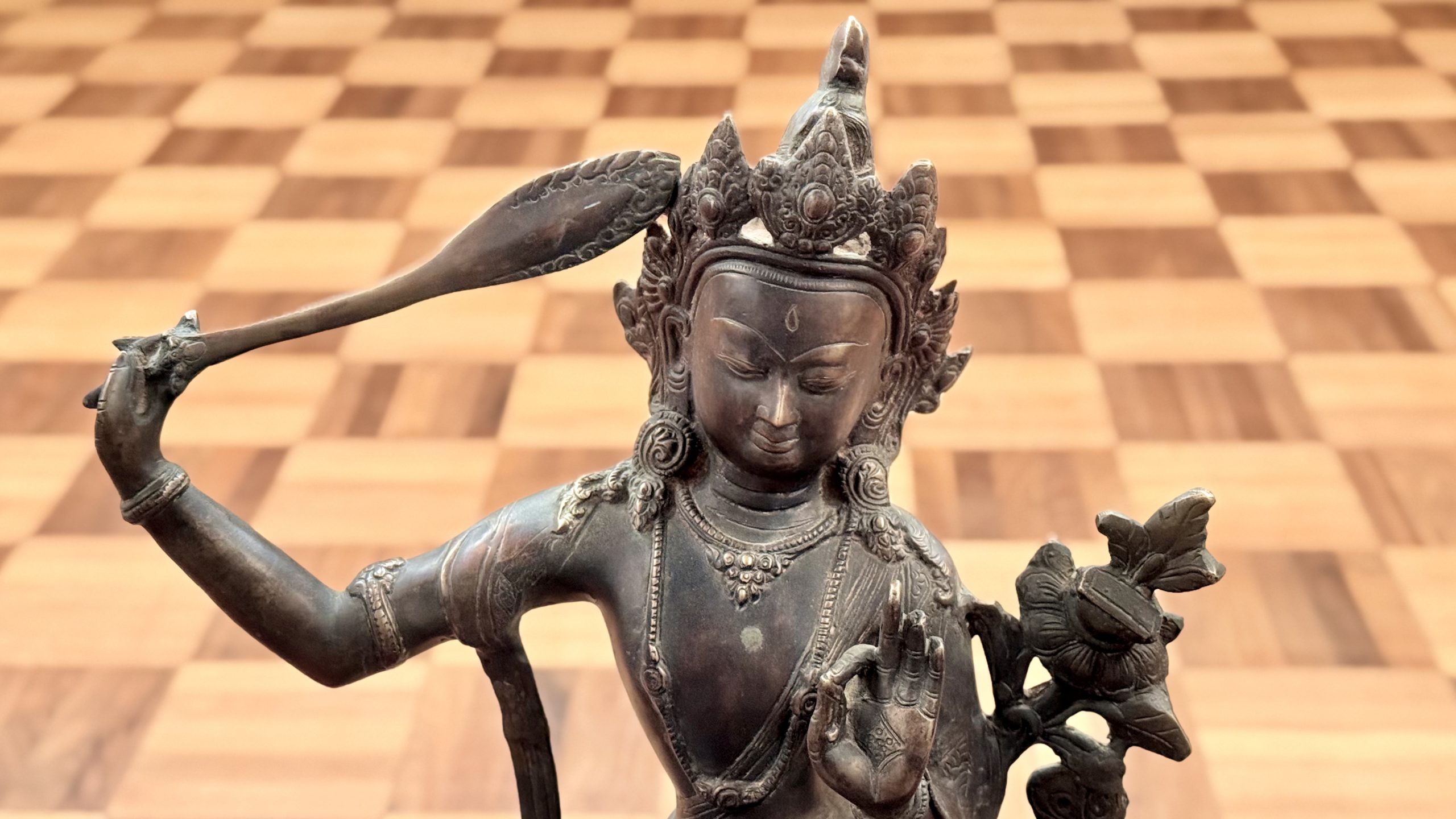Manjusri against the background of wooden, tiled floor